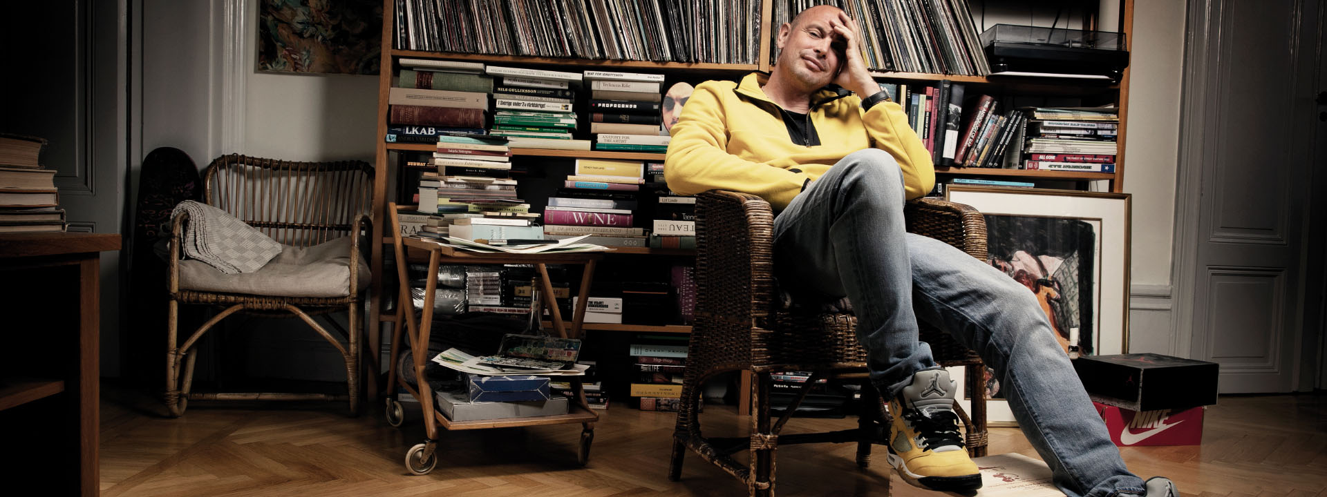 Artisten Petter sitter i en stol framför en bokhylla
